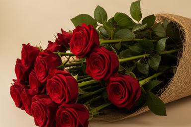 Ramo de rosas rojas de tallo largo con follaje verde y envoltorio natural preparado para regalo